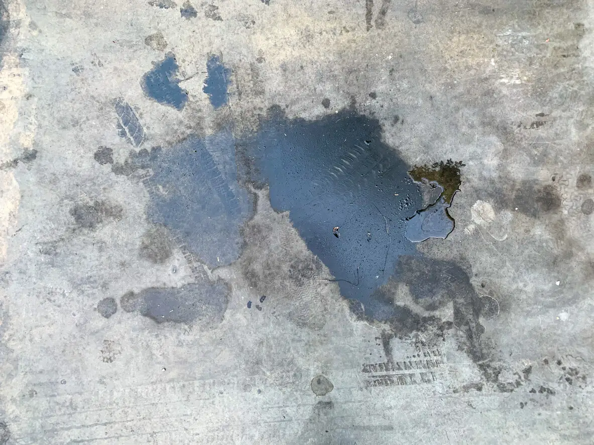 Visible oil stains on an untreated concrete parking surface. Highlights the need for proper sealing to prevent damage and long-term discoloration