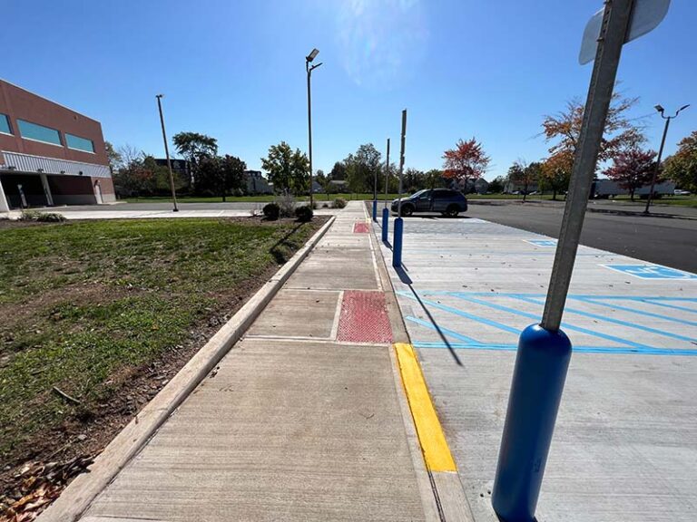 ADA-compliant sidewalk with curb ramps, warning pads, and accessible path to handicap parking near commercial building