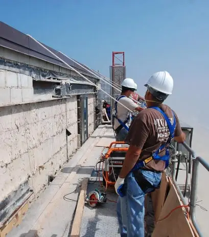 Construction workers in safety gear and harnesses operate on a high-rise scaffold, highlighting T.G. Basile’s job site safety focus