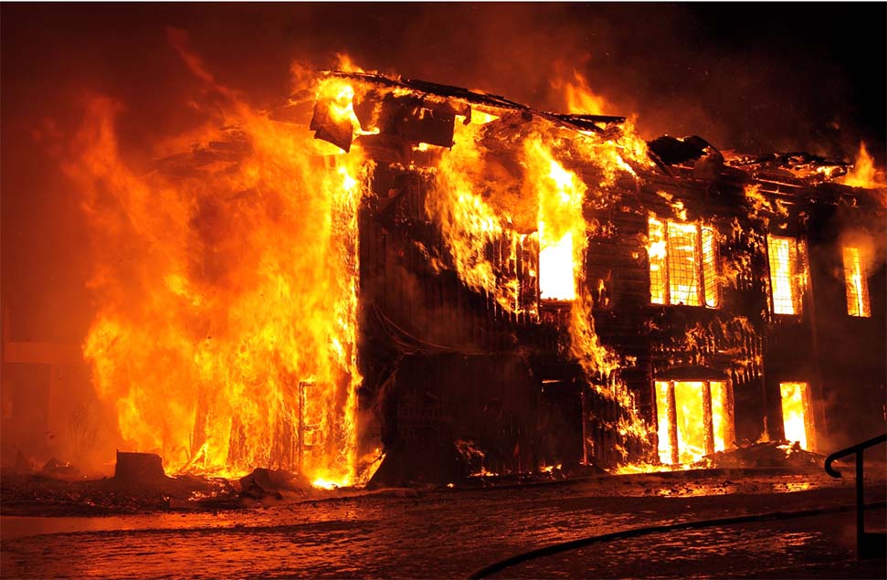 A multi-story building consumed by flames at night, illustrating the destructive force of fire and the urgency of effective fire-resistant materials