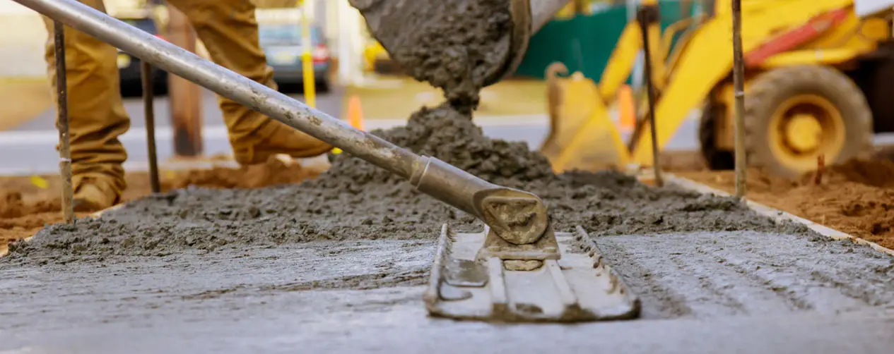 Fresh concrete being poured and leveled, illustrating essential steps in achieving proper strength for long-lasting surfaces