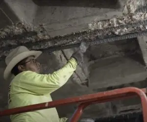 Construction professional repairs deteriorated concrete and exposed rebar on ceiling, enhancing structure's durability and safety