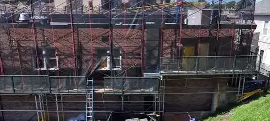 Scaffolding surrounds a historic brick building in Yonkers, NY, as crews perform detailed façade repairs and preservation work