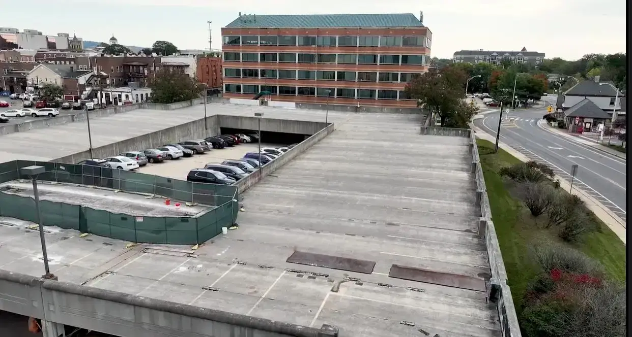 Aerial view of a Somerville, NJ parking garage undergoing surface repairs, with fenced-off work zones and active car parking below