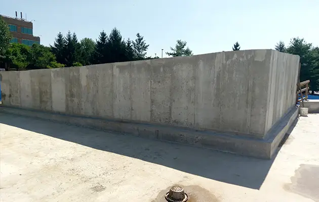 Finished reinforced concrete wall structure on a wide slab foundation, complete with drainage and safety railings on one side