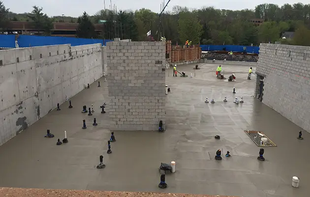 Freshly poured structural concrete slab with foundational plumbing set, forming a solid base for vertical construction