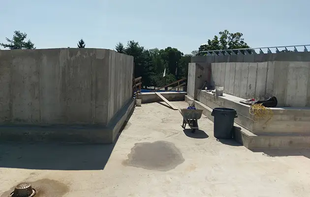 Completed concrete walls and elevated slab platform with tools and materials staged for continued structural or utility work