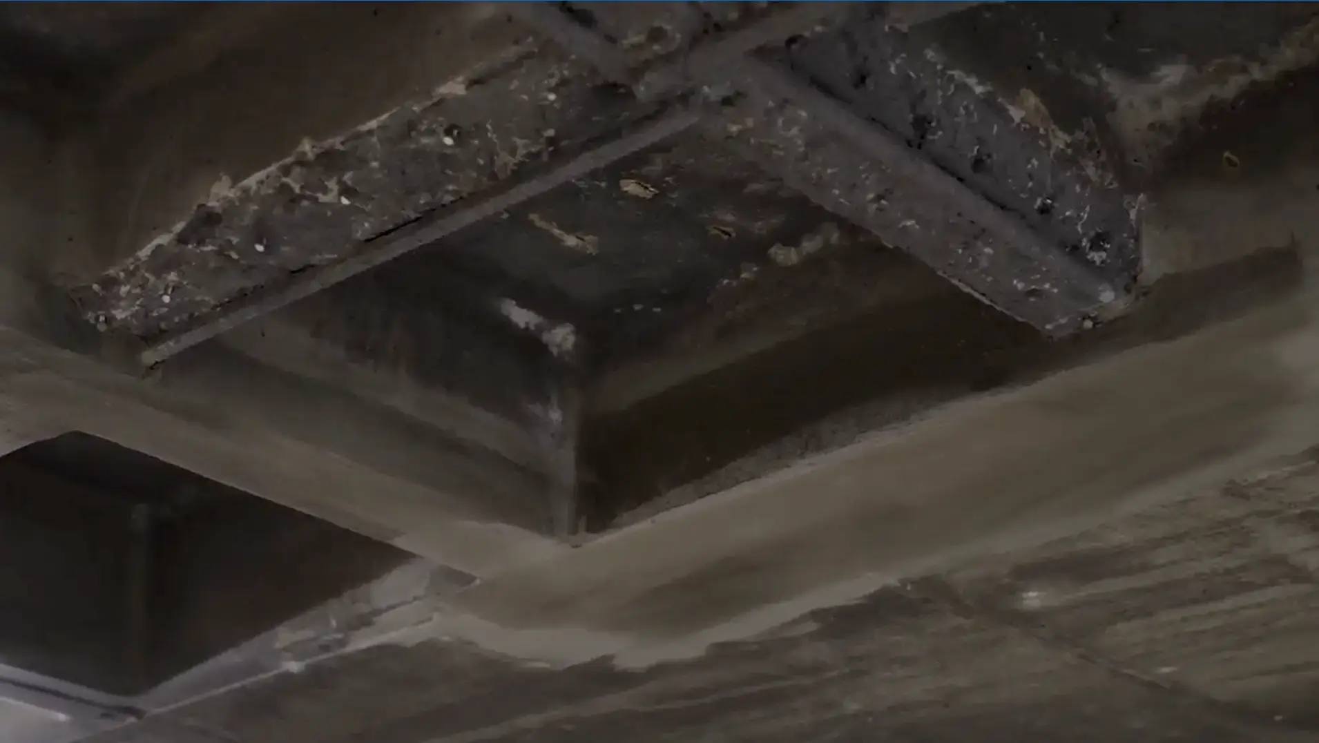 Damaged concrete beam in parking structure indicating need for restoration