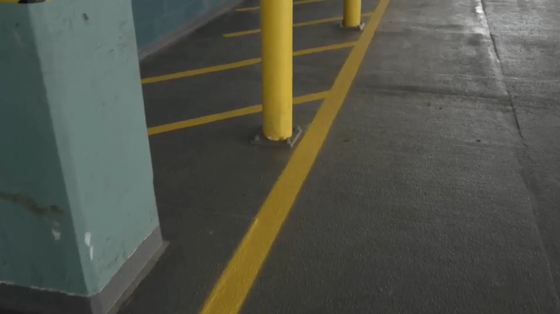 Faded yellow lines and protective bollards in an aging parking garage