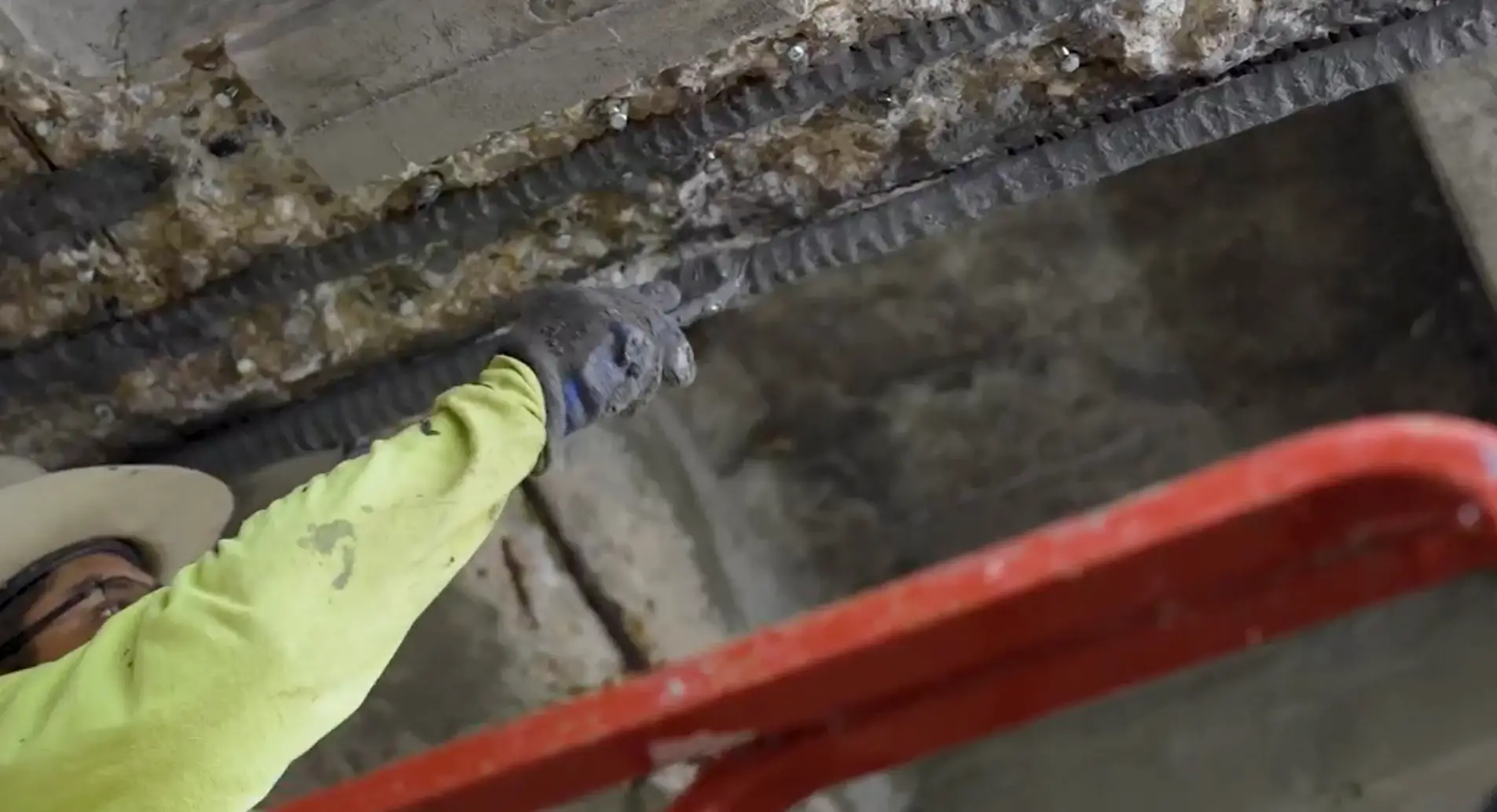 Worker repairing exposed rebar in a concrete ceiling during parking garage structural restoration and maintenance.