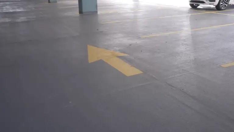 Yellow directional arrow painted on garage floor, helping optimize traffic flow and improve navigation in parking structure design