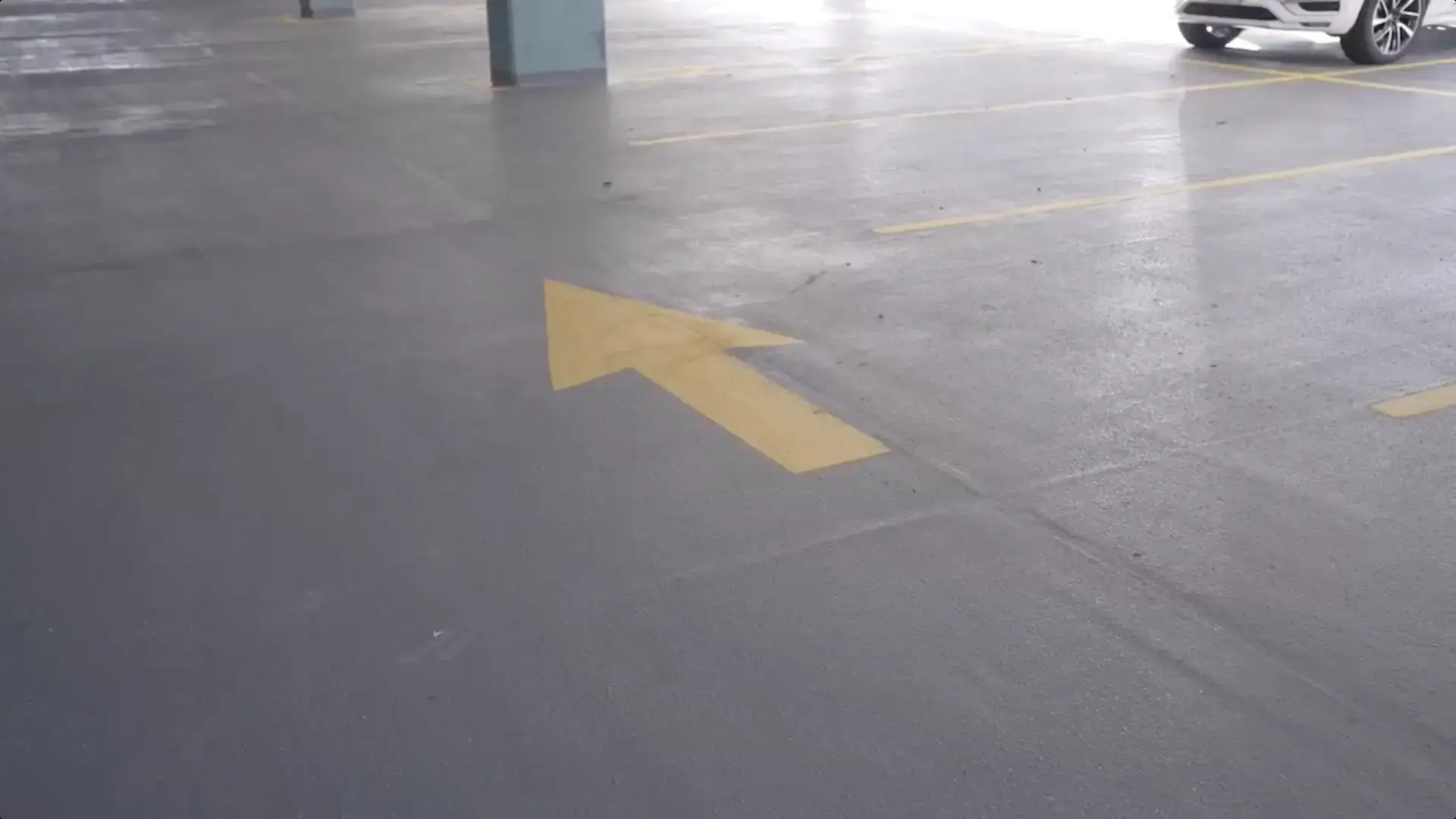 Yellow directional arrow painted on garage floor, helping optimize traffic flow and improve navigation in parking structure design