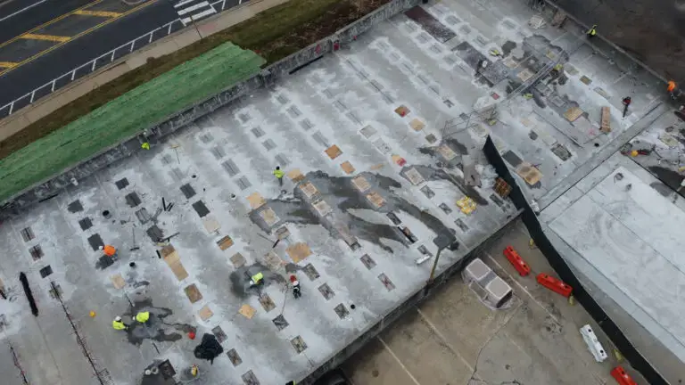 Aerial view of a parking garage undergoing structural deck repairs. Workers patch deteriorated concrete areas to restore safety and extend the structure’s life