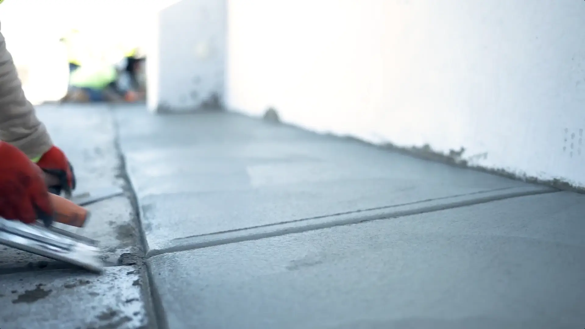 Close-up of a worker smoothing freshly poured concrete, showcasing attention to detail during parking garage surface prep