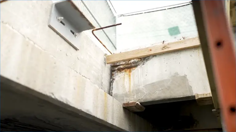 Corroded rebar and rust stains show severe weather damage to concrete, compromising parking garage safety and durability
