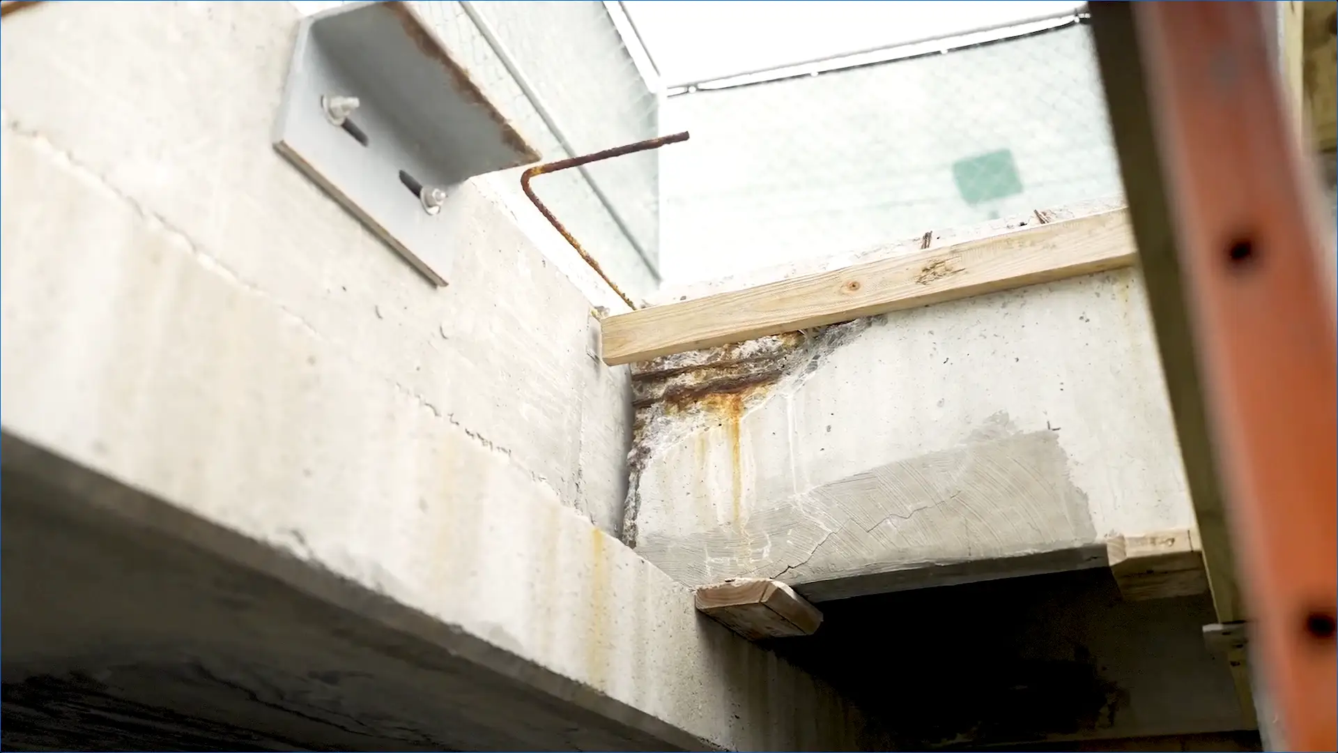 Corroded rebar and rust stains show severe weather damage to concrete, compromising parking garage safety and durability