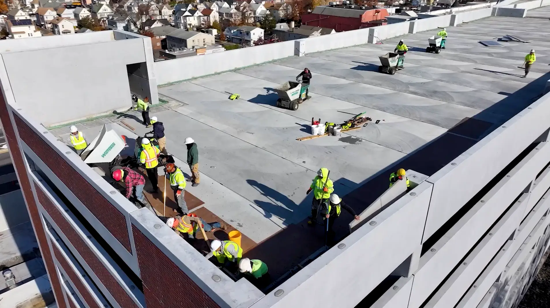 Aerial view of a rooftop parking garage under construction, with workers installing materials and equipment on-site