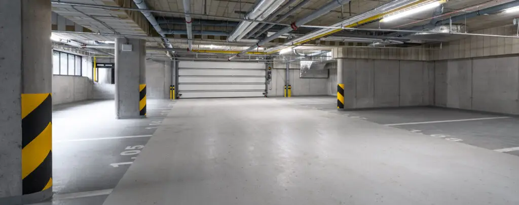 Bright and clean underground parking garage with clear markings and safety bumpers showing results of regular maintenance