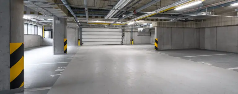 Bright and clean underground parking garage with clear markings and safety bumpers showing results of regular maintenance