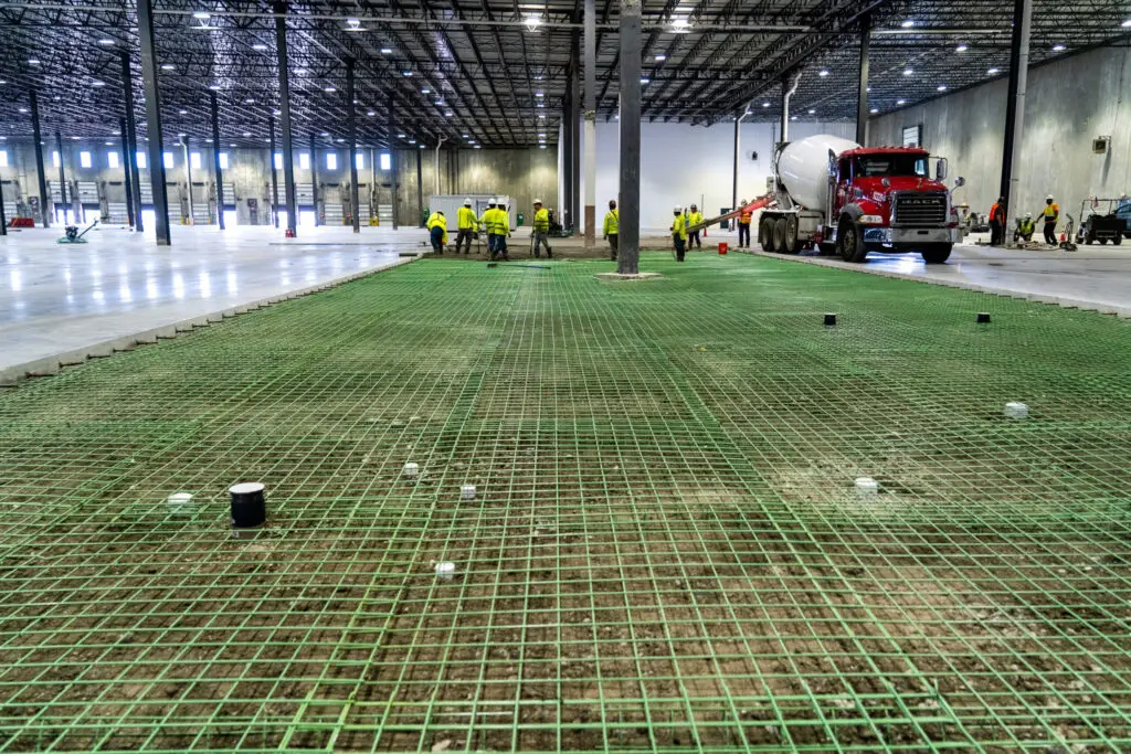 Warehouse tenant improvement in progress with rebar grid and concrete pour preparation by crew and mixer truck